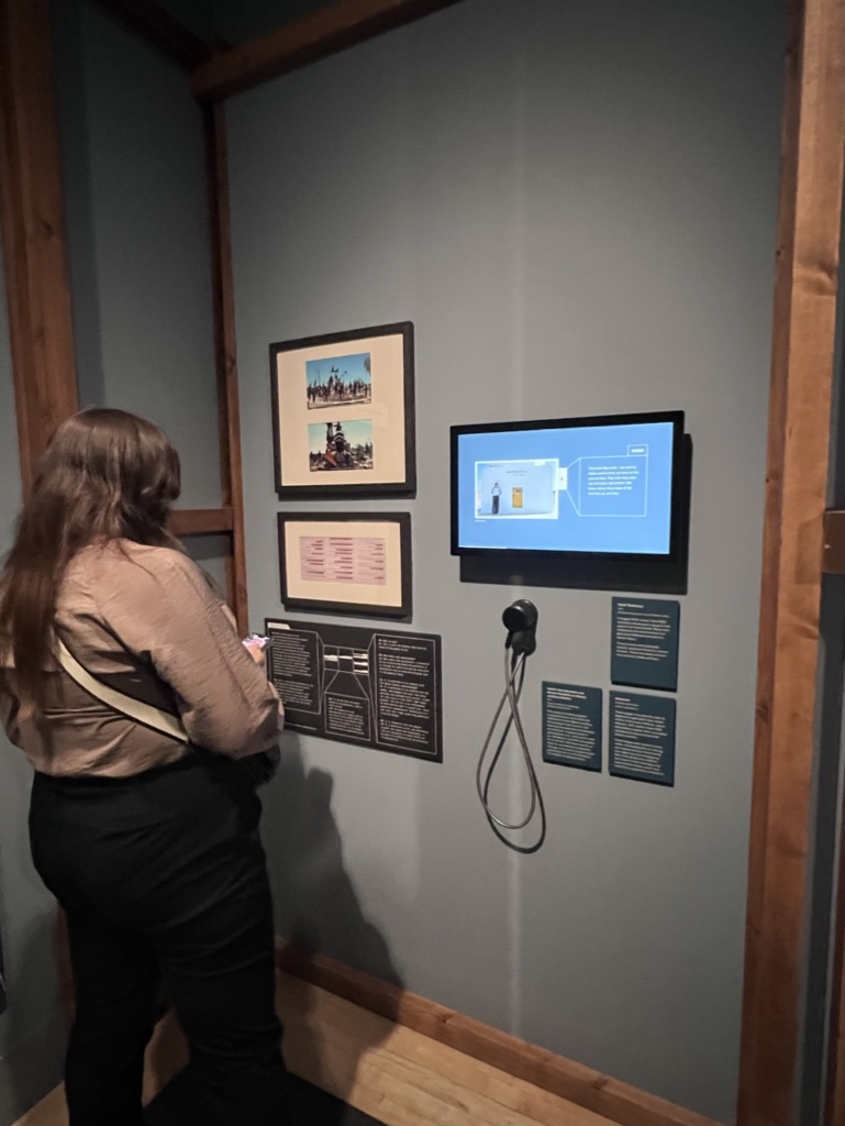 A musuem-goer interacting with an exhbit allowing them to listen to some of the testimonies. 